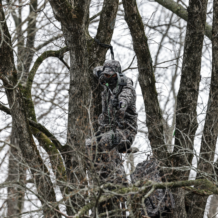 hunter wearing asio raptor camo at full draw on a whitetail during late season bow hunt
