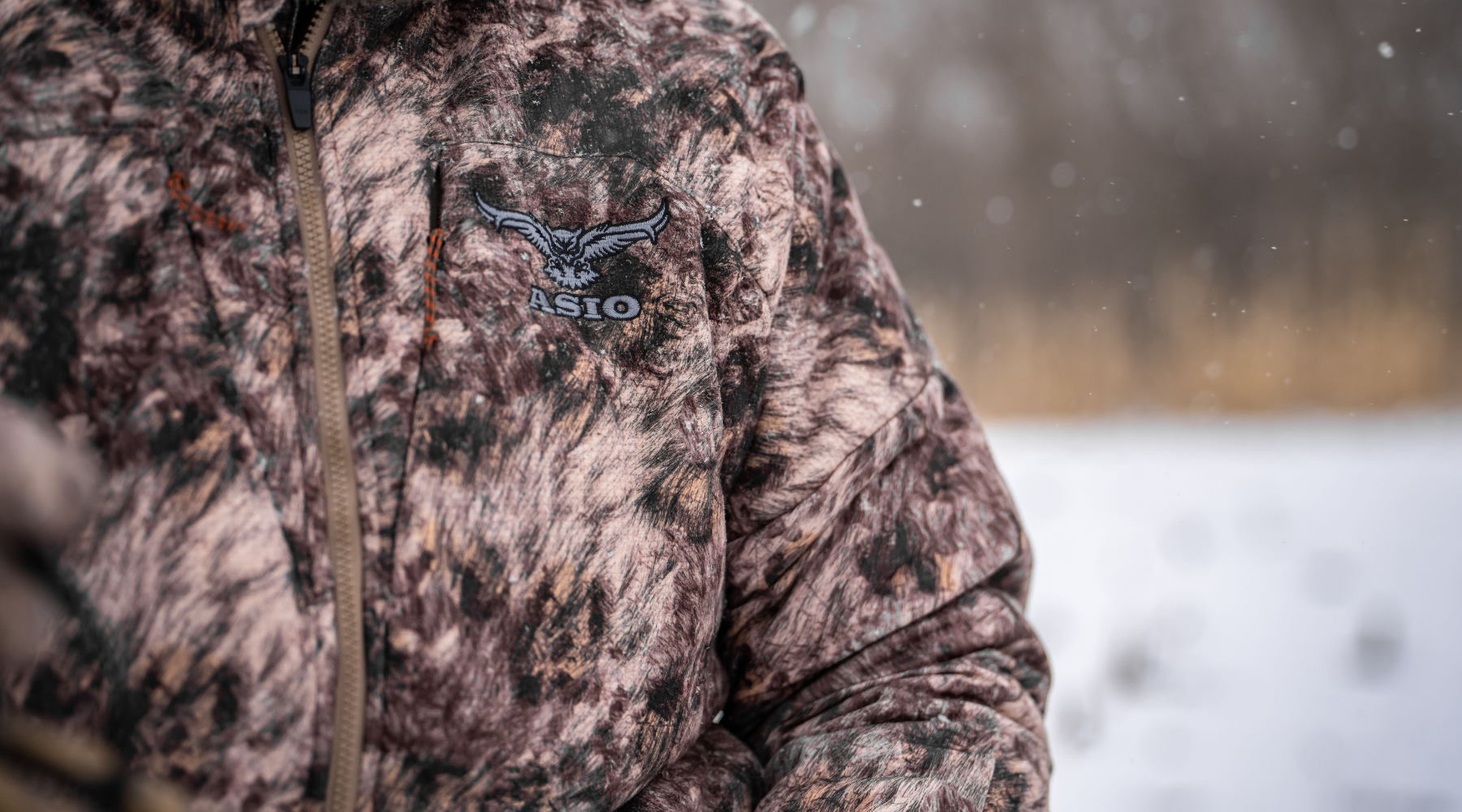 hunter wearing asio gear rapx camo walking into a sunset in a grass field