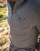 Close-up of a hunter wearing the ASIO Gear Heavyweight Baselayer Top in solid gray, showing the ASIO logo and performance fabric details.