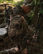 Hunter kneeling in ASIO Gear RAPTOR camo lightweight hoodie preparing gear for early season whitetail hunt