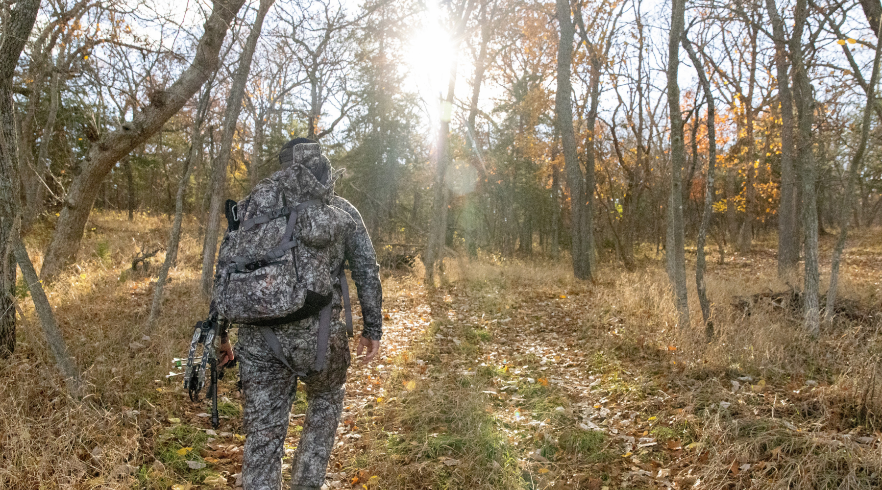 bowhunter entering woods for a whitetail hunt during the rut wearing a full set of asio raptor camo - optimized for desktop